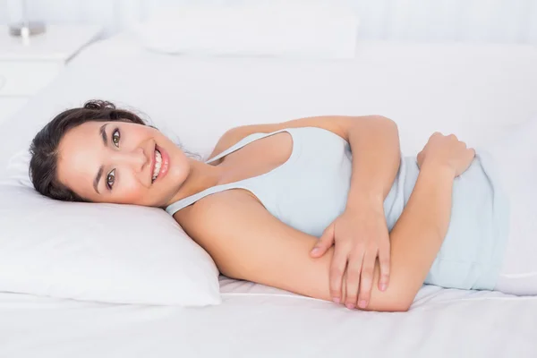 Улыбающаяся красивая молодая женщина отдыхает в постели — стоковое фото