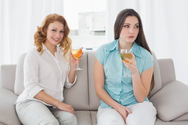 Female friends with wine glasses sitting on sofa — Stock Photo, Image