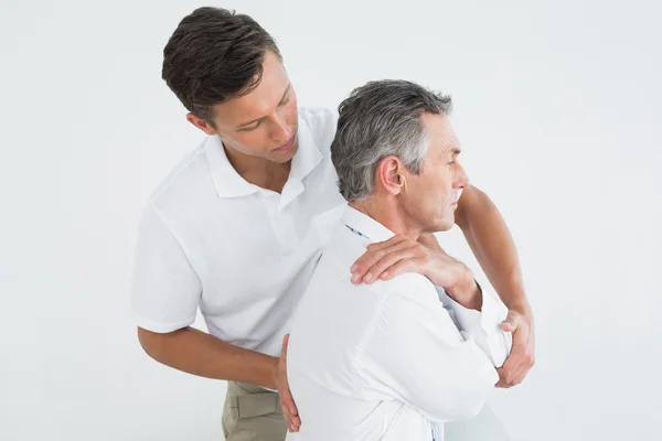 Mannelijke chiropractor onderzoekende volwassen man — Stockfoto