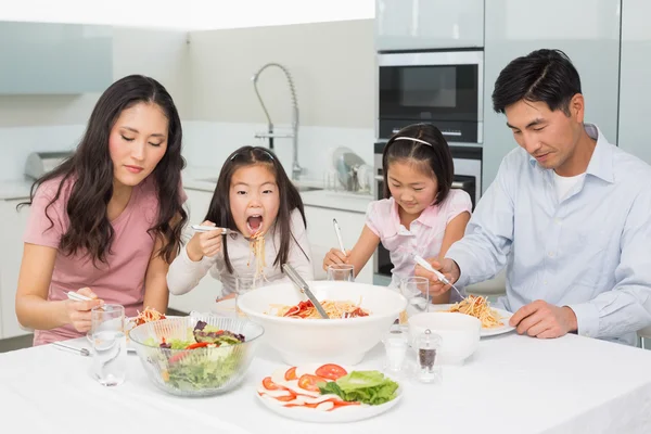 Heureuse famille de quatre personnes dégustant des spaghettis déjeuner en cuisine — Photo