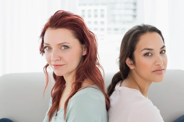 Two beautiful young female friends sitting back to back — Stock Photo, Image