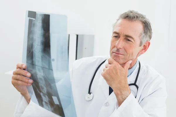 Doctor mirando la imagen de rayos X de la columna vertebral en la oficina —  Fotos de Stock