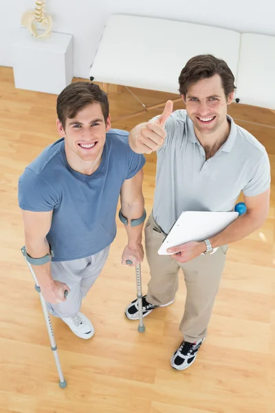 Male therapist gesturing thumbs up with disabled patient — Stock Photo, Image