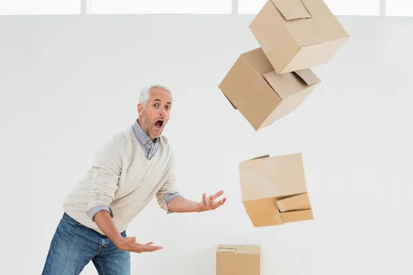 Side view of a mature man with falling boxes — Stock Photo, Image