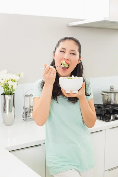 Portrait of a young woman eating salad in kitchen — Stock Photo, Image