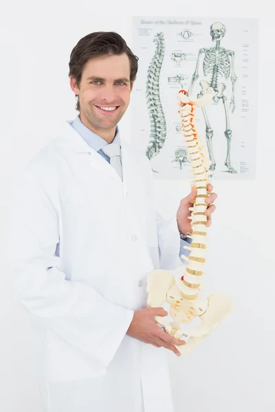 Iskelet modeli ile gülümseyen bir erkek doktor portresi — Stok fotoğraf