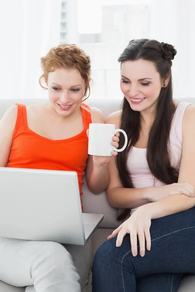 Amigos femeninos usando el ordenador portátil juntos en casa —  Fotos de Stock