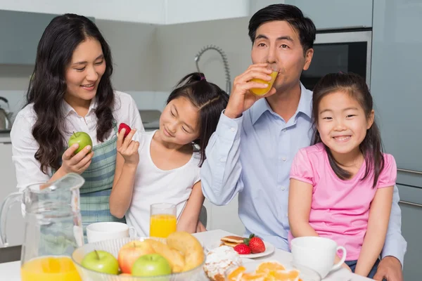 Cheerful family of four enjoying healthy breakfast in kitchen — Stock Photo, Image