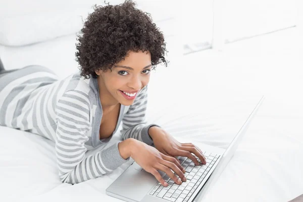 Sorrindo jovem mulher usando laptop na cama — Fotografia de Stock