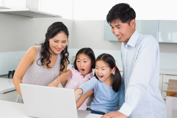 Familia conmocionada de cuatro usando el ordenador portátil en la cocina — Foto de Stock