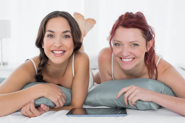 Two female friends with digital table lying in bed — Stock Photo, Image