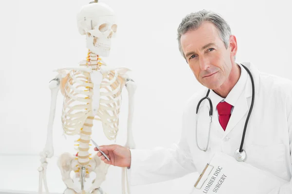 Médico de confianza explicando la columna vertebral en el consultorio —  Fotos de Stock