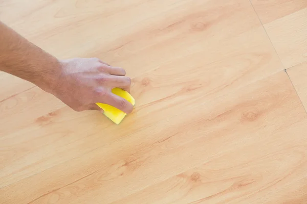 Mano con spugna pulire il pavimento in parquet a casa — Foto Stock