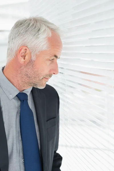 Serious mature businessman peeking in the office — Stock Photo, Image