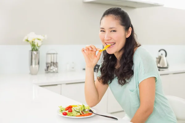 Portret van een jonge vrouw salade eten in keuken — Stockfoto