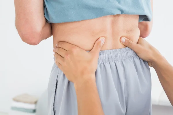 Handen masseren mans lagere terug in gym ziekenhuis — Stockfoto