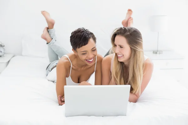 Feliz relaxado amigos do sexo feminino usando laptop na cama — Fotografia de Stock