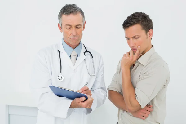 Doctor discutiendo informes con el paciente en el consultorio —  Fotos de Stock