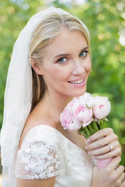 Bella sposa sorridente che tiene il suo bouquet indossando un velo — Foto Stock