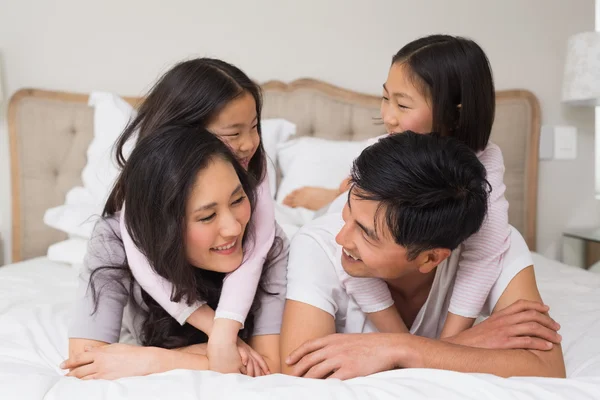 Familia cariñosa de cuatro tumbados en la cama en casa — Foto de Stock