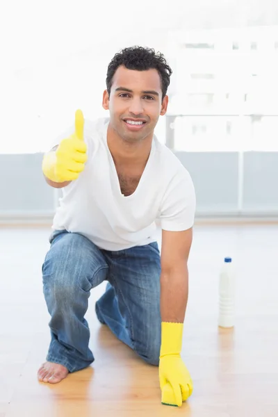 Usmívající se muž čištění podlahy a zároveň ukázal dobrý znamení — Stock fotografie