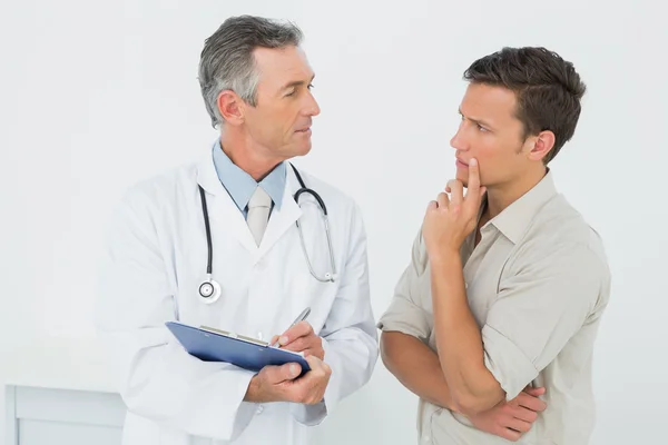 Médico discutindo relatórios com paciente no consultório — Fotografia de Stock
