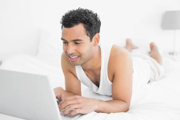 Casual man met laptop in bed — Stockfoto