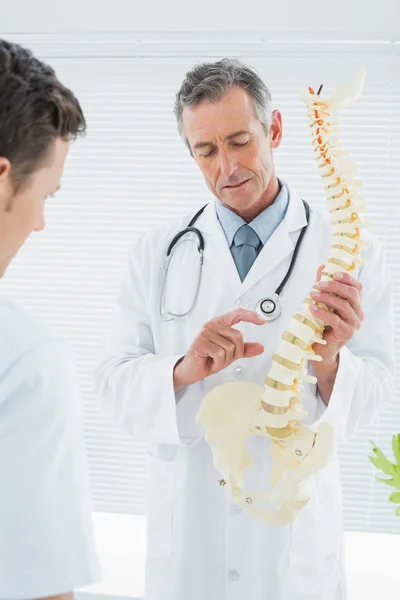 Médico explicando a coluna vertebral ao paciente no consultório — Fotografia de Stock