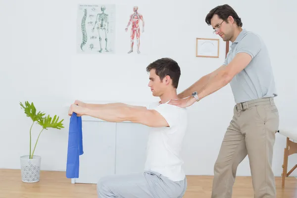 Mannelijke therapeut helpen jonge man met oefeningen — Stockfoto