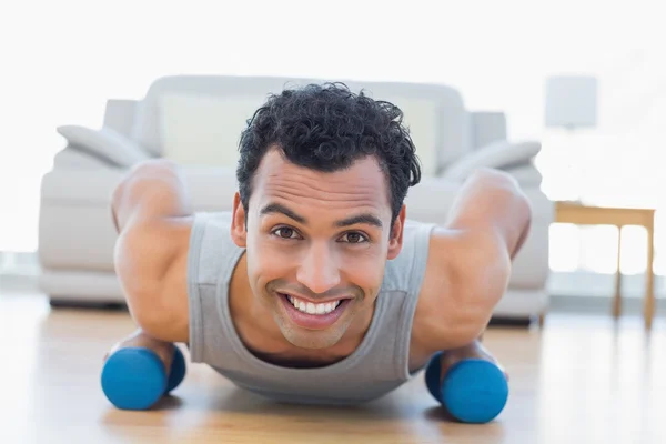 Man with dumbbells doing push ups in the living room — Stock Photo, Image