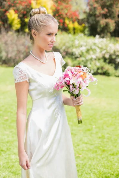 Pretty blonde bride holding lily bouquet — Stock Photo, Image