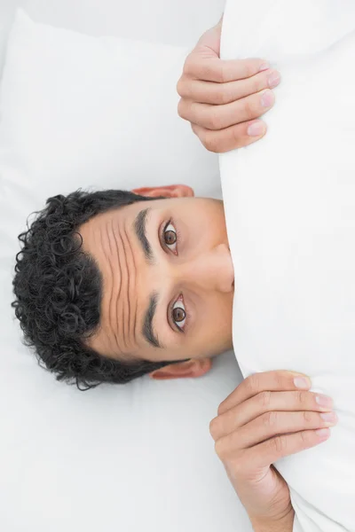 Hombre sorprendido cubriendo la cara con sábanas en la cama —  Fotos de Stock