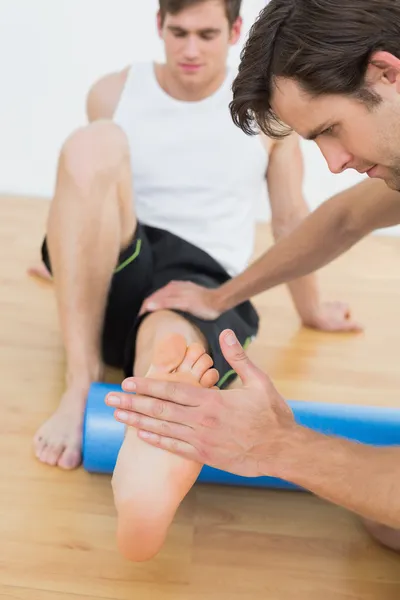 Physiothérapeute examinant une jambe de jeunes hommes — Photo