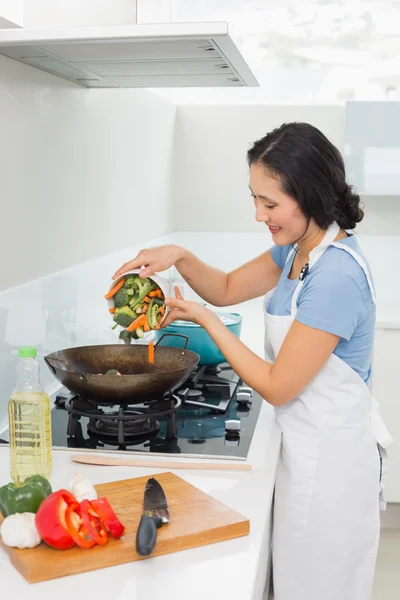 Souriant jeune femme préparant la nourriture dans la cuisine — Photo