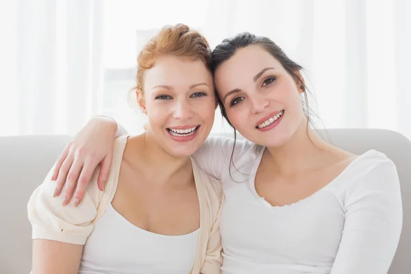 Felices amigas con brazo alrededor en la sala de estar —  Fotos de Stock