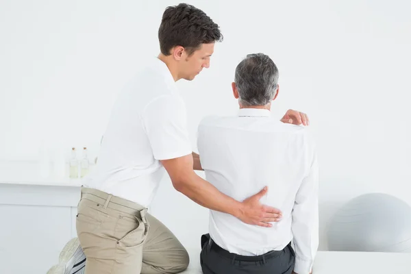 Male chiropractor examining mature man — Stock Photo, Image