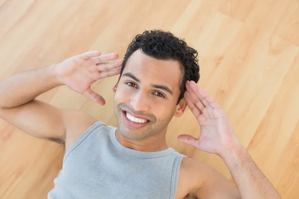 Uomo sorridente che fa scricchiolii addominali sul pavimento in parquet — Foto Stock