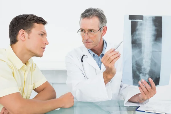 Médico que explica a radiografia dos pulmões ao paciente no consultório — Fotografia de Stock