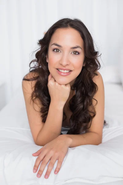 Portrait of a smiling brunette lying in bed — Stock Photo, Image