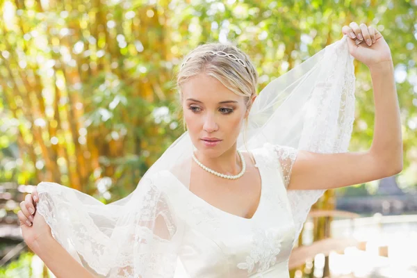 Calm blonde bride holding her veil out — Stock Photo, Image