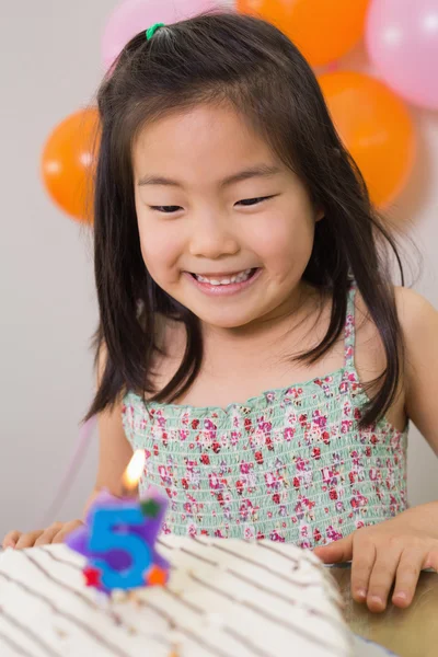 Cute girl looking at cake at her birthday party — Stock Photo, Image