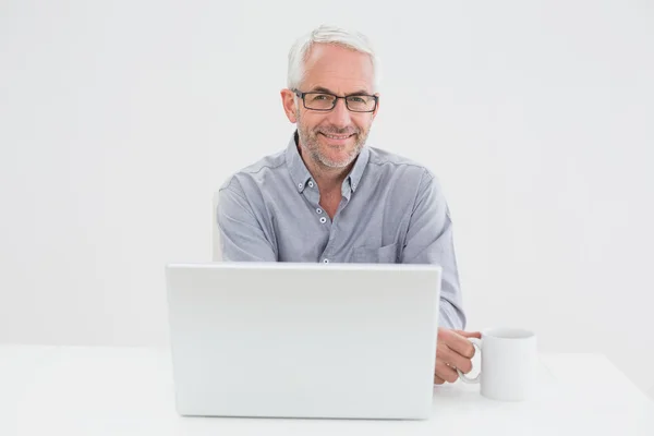 微笑成熟的商人与笔记本电脑和咖啡的杯 — 图库照片
