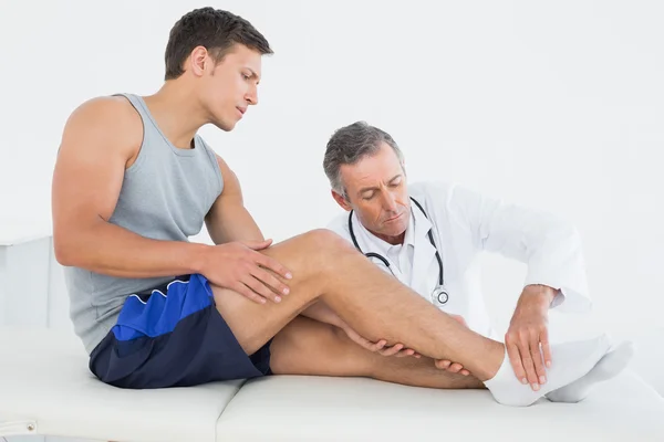 Side view of a young man getting his leg examined — Stock Photo, Image