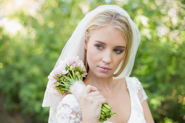 Sposa pacifica che tiene il suo bouquet indossando un velo — Foto Stock