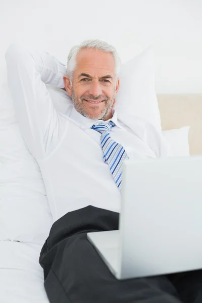 Zrelaksowany biznesmen dojrzały w laptopie w łóżku — Zdjęcie stockowe