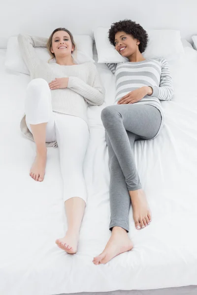 Två avslappnade unga kvinnliga vänner i sängen — Stockfoto