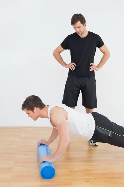 Physical therapist watching young man do push ups — Stock Photo, Image