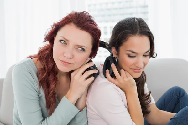 Vrienden luisteren muziek via de koptelefoon samen thuis — Stockfoto