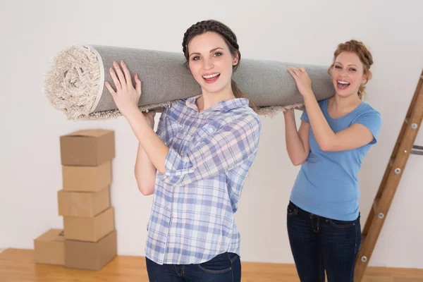 Vrolijke vrienden uitvoering tapijt gerold na zijn verhuizing in een huis — Stockfoto