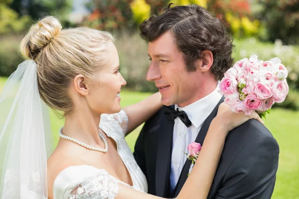 Bride and groom embracing and smiling at each other — Stock Photo, Image